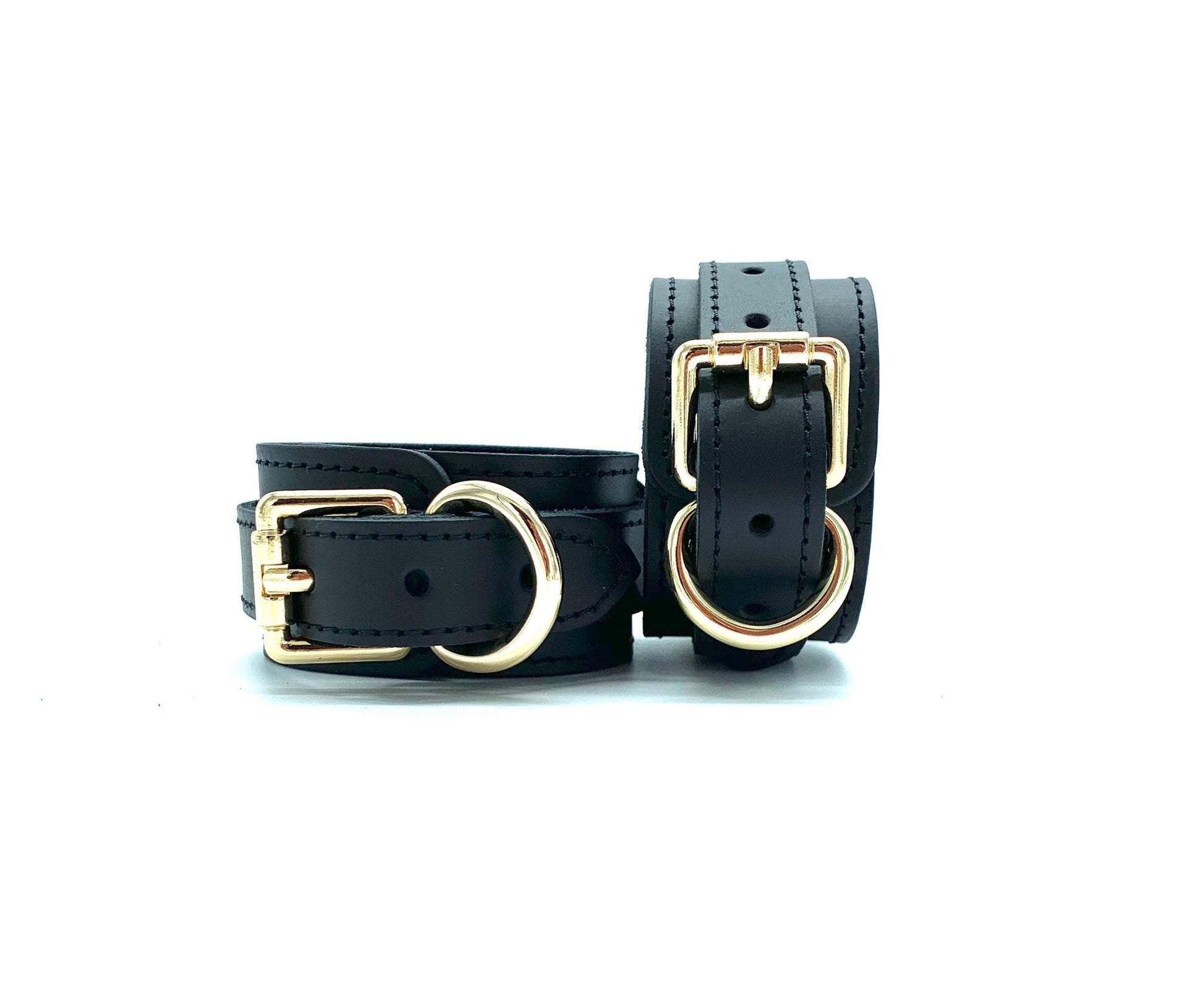 Pair of BDSM cuffs in the Tango Black BDSM Set, made of Italian leather with black stitching and gold hardware, perfect for secure, comfortable bondage play.