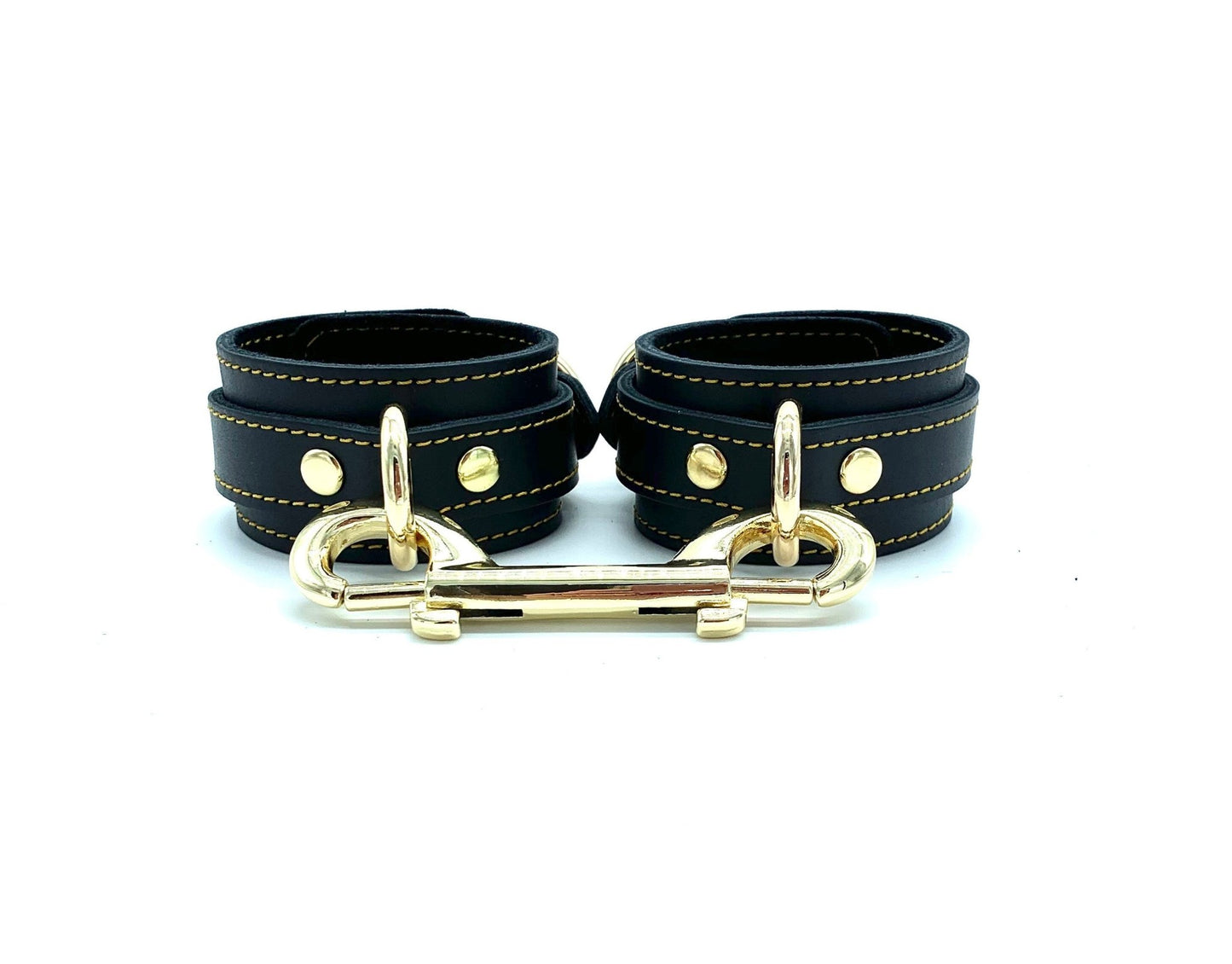 Pair of BDSM cuffs in the Tango Black BDSM Set, crafted from Italian leather with gold stitching and gold hardware, perfect for secure, comfortable bondage play.