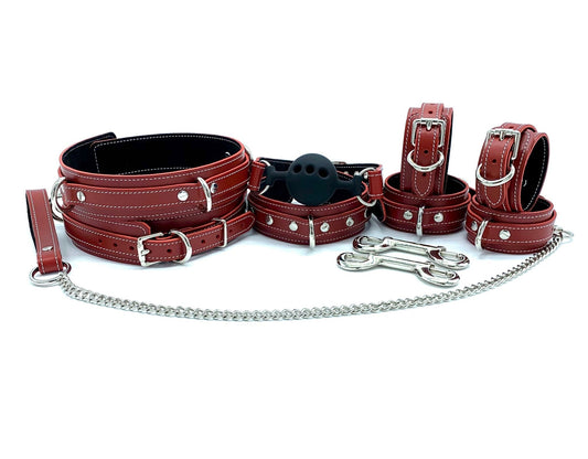 Tango Red BDSM Kit displaying the complete luxury leather bondage set, featuring thigh cuffs, ankle and hand cuffs, a ball gag, and a collar with leash. Crafted in red leather with black suede and white stitching, all complemented by silver hardware. This comprehensive set offers a sophisticated selection of BDSM gear for enhanced play.