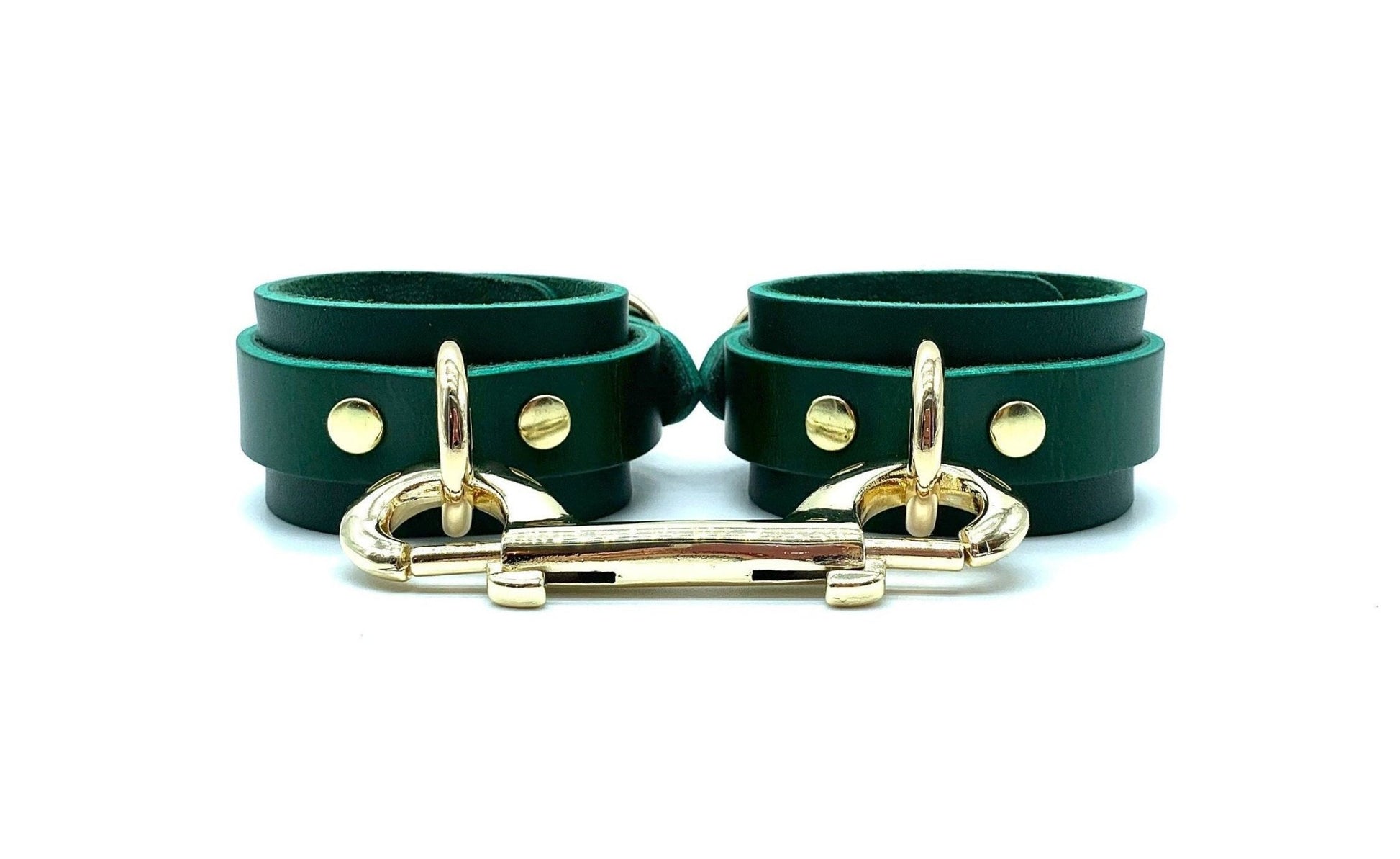 Green leather handcuffs with black suede, linked by striking gold connectors, offering a sophisticated look for BDSM accessories, emphasizing style, comfort, and secure fit, expertly made in the USA.