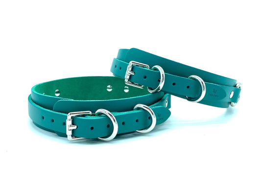"Luxurious Italian leather thigh cuffs in a rich teal color with silver-tone hardware, adjustable buckle closures, and embossed branding