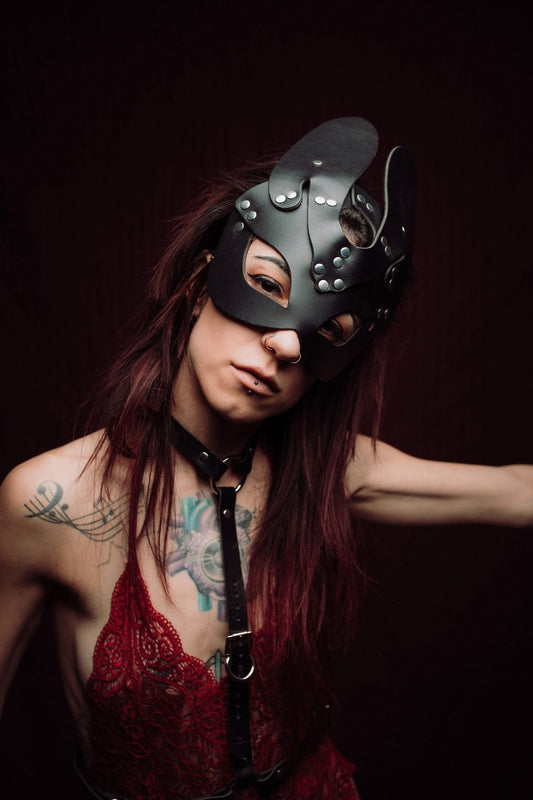 Lady Wearing a Black Mask and Harness: A lady dressed in a sophisticated black mask paired with a leather harness, both made from high-quality materials. The mask features sleek contours and the harness complements the mask, enhancing her mysterious and elegant appearance.