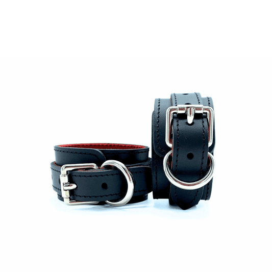 Black leather cuffs with red lining and silver hardware, pair of adjustable cuffs with buckle detail