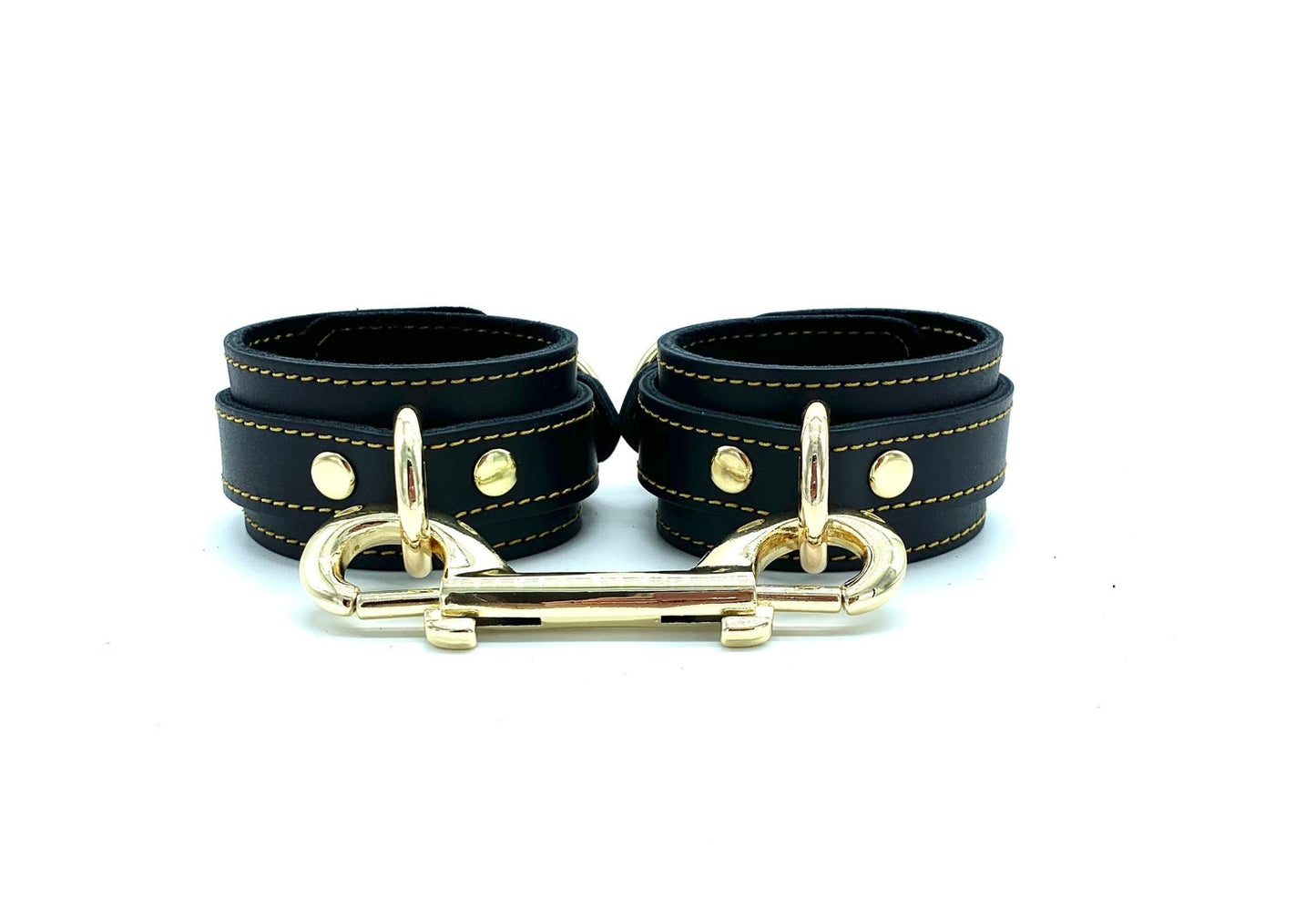 Italian leather BDSM bondage cuffs made in the USA, showcasing Tango black leather and black suede cuffs with intricate gold stitching, accompanied by gold hardware and a gold connector, radiating elegance and quality craftsmanship.