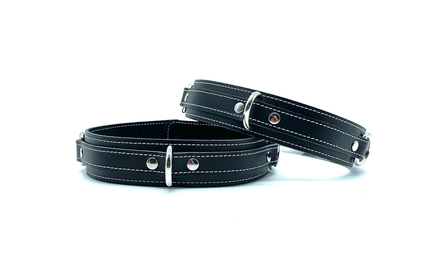 Front view of lulexy Tango Black Italian leather BDSM bondage thigh cuffs, focusing on the prominent silver D-rings attached to the opulent black leather, set against a simple backdrop for maximum visual impact.