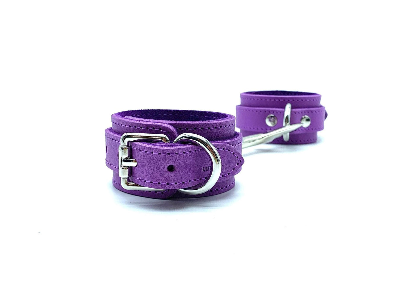 Italian suede and leather BDSM bondage cuffs made in the USA, featuring Tango purple cuffs connected by a connector, displaying exquisite silver hardware, ideal for secure and stylish restraint during bondage play.