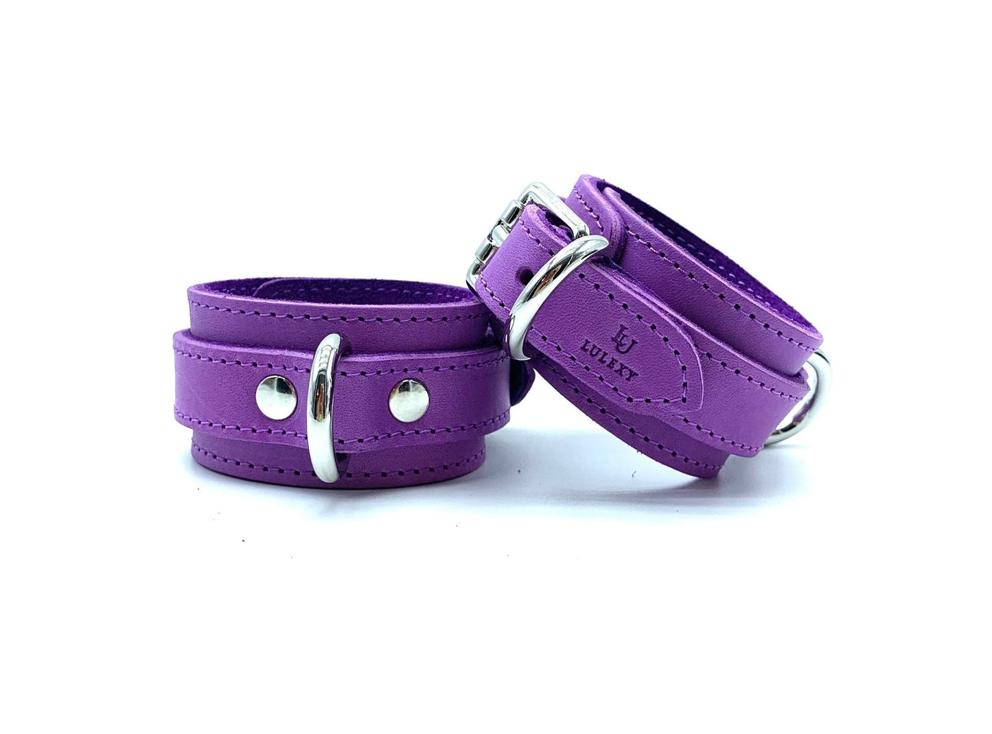 Italian leather and suede BDSM bondage cuffs made in the USA, displaying Tango purple cuffs arranged vertically, with one cuff on the bottom and the second on the top, both adorned with silver hardware, offering versatility and comfort for various play scenarios.