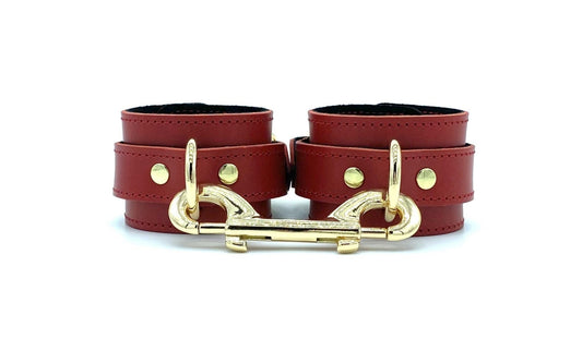 Italian leather and suede BDSM bondage 2" cuffs made in the USA, featuring Tango red leather and black suede cuffs positioned side by side, adorned with lavish gold hardware and a matching connector, offering both style and security for passionate bondage enthusiasts.