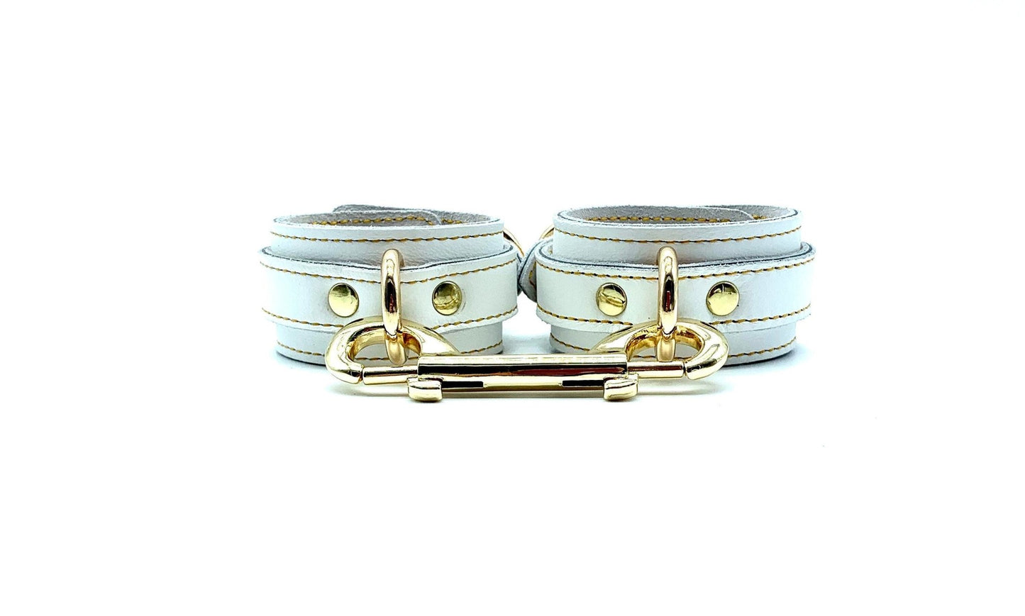 Italian white leather and suede BDSM bondage cuffs made in the USA, linked together by a robust gold connector and embellished with lavish gold hardware, ensuring a seamless blend of style and functionality for discerning bondage enthusiasts.