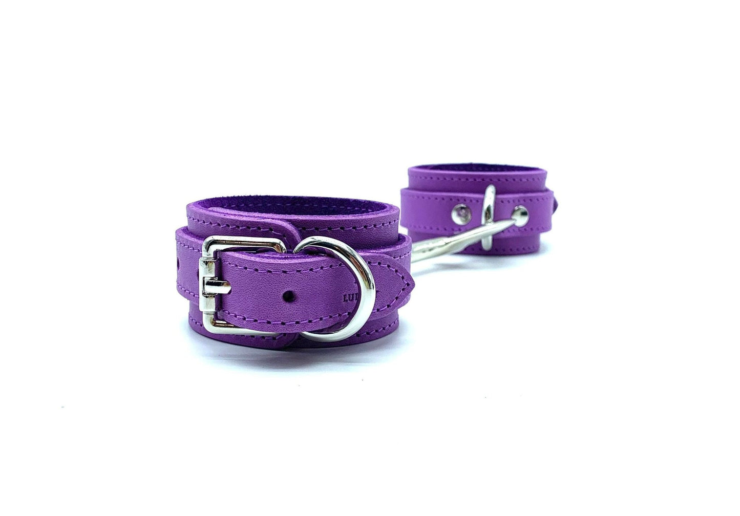 Set of four purple leather cuffs displayed next to each other, connected by a gold connector, highlighting the luxurious and custom BDSM gear.