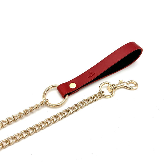 close up of detachable gold chain leash with red leather handle and Lulexy logo on it.