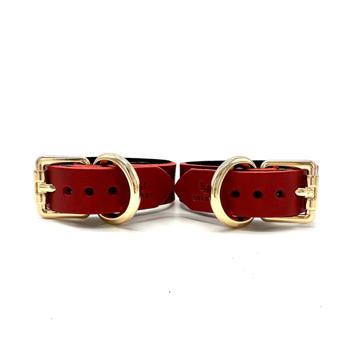 A pair of red leather cuffs with buckle closure and Lulexy logo
