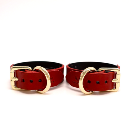 A pair of red leather cuffs with buckle closure and Lulexy logo