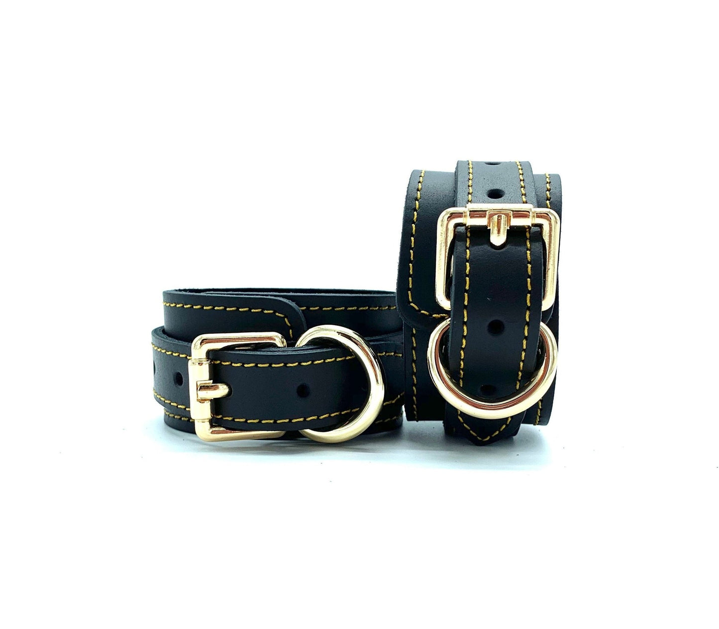 Close up of black leather handcuffs featuring detailed gold stitching and elegant gold buckle.