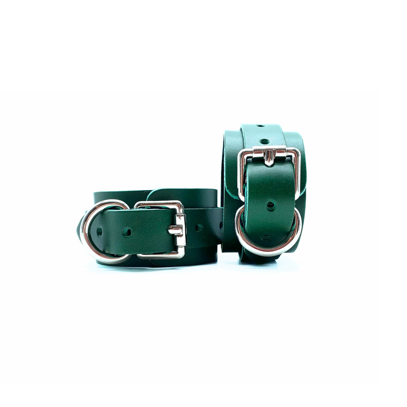 A pair of green leather handcuffs showcasing elegant silver buckle and multiple adjustment holes.