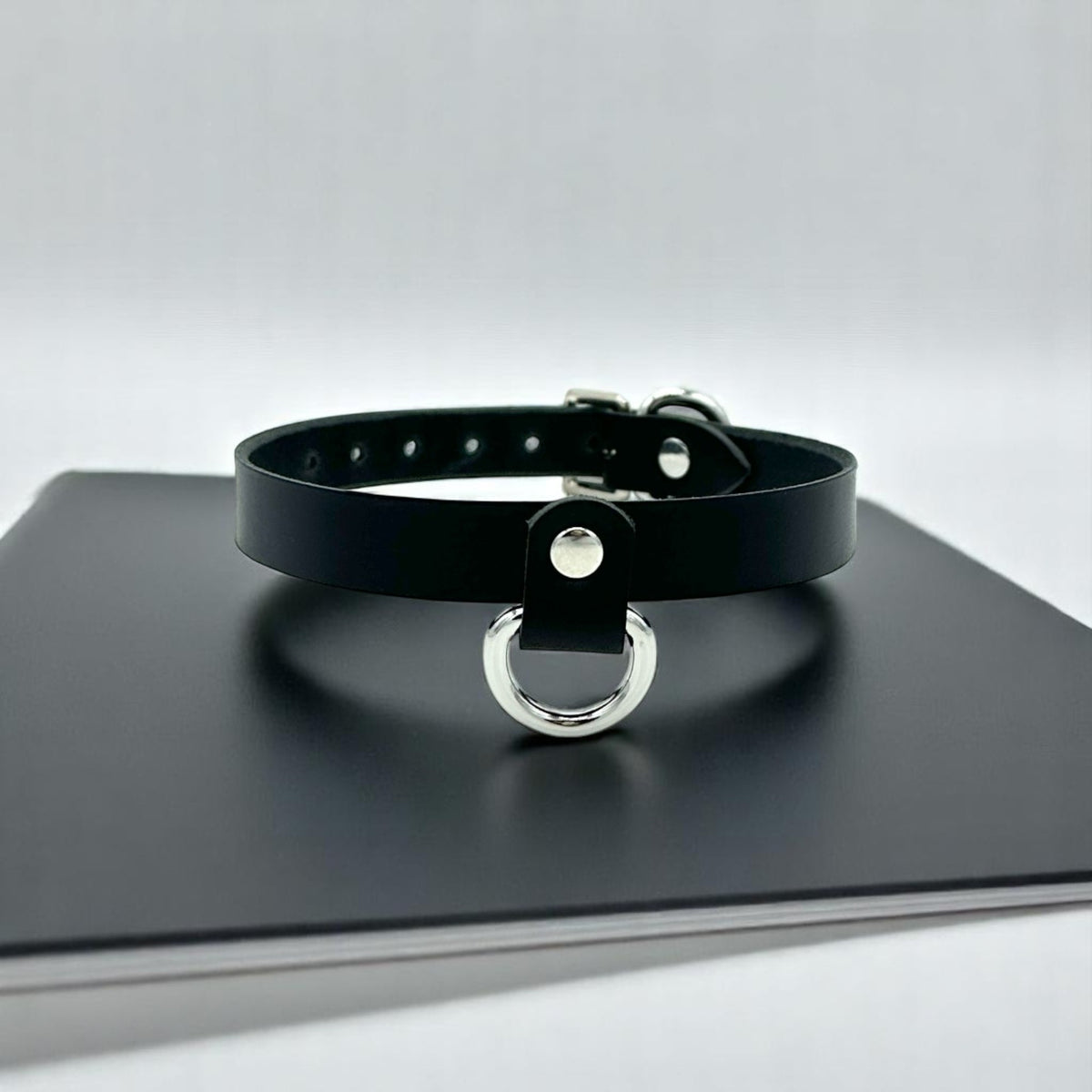 Black Italian leather choker featuring a silver D-ring suspended from a short leather tab at the center front.