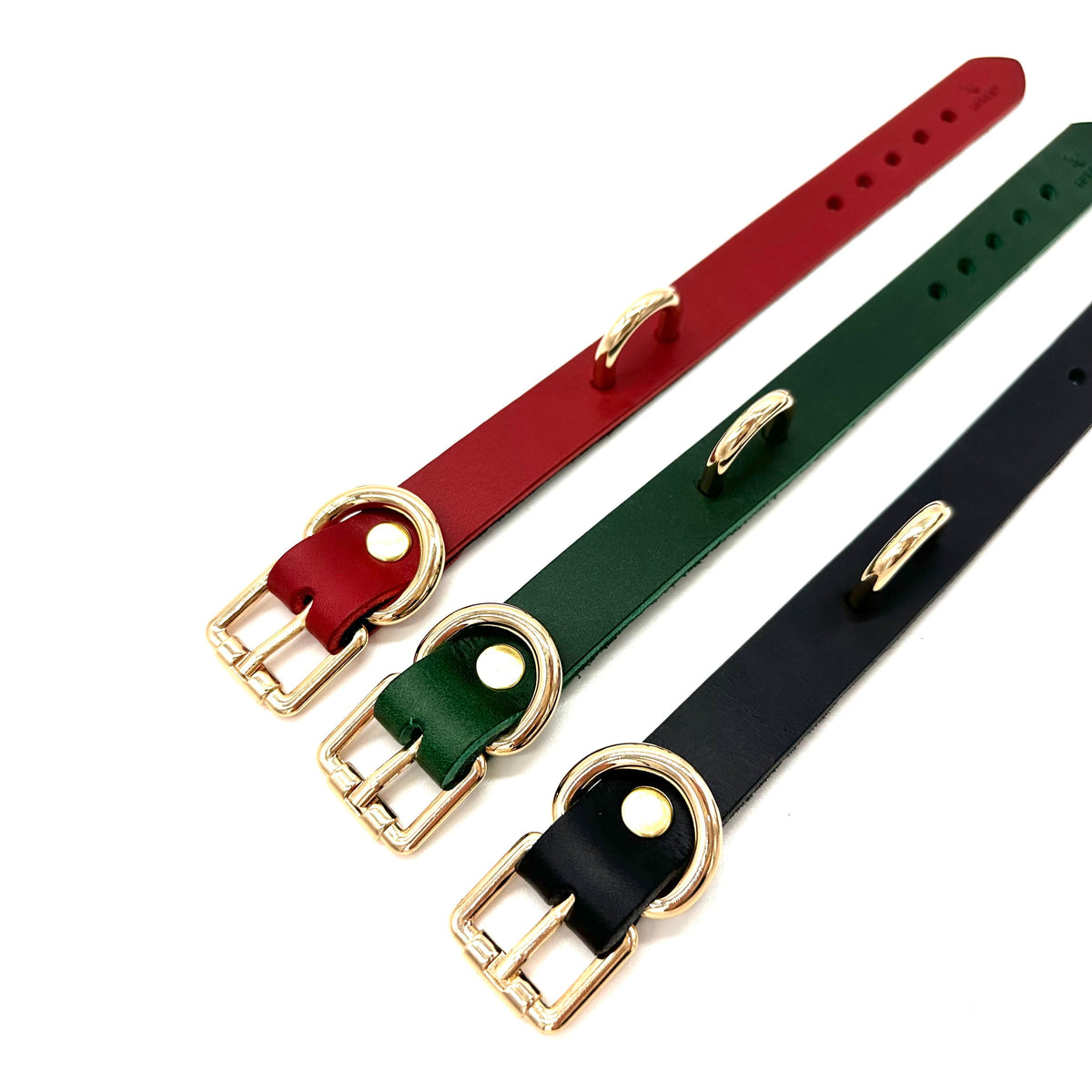 Flat lay image of Rio cuffs in red, green and black leather with gold hardware