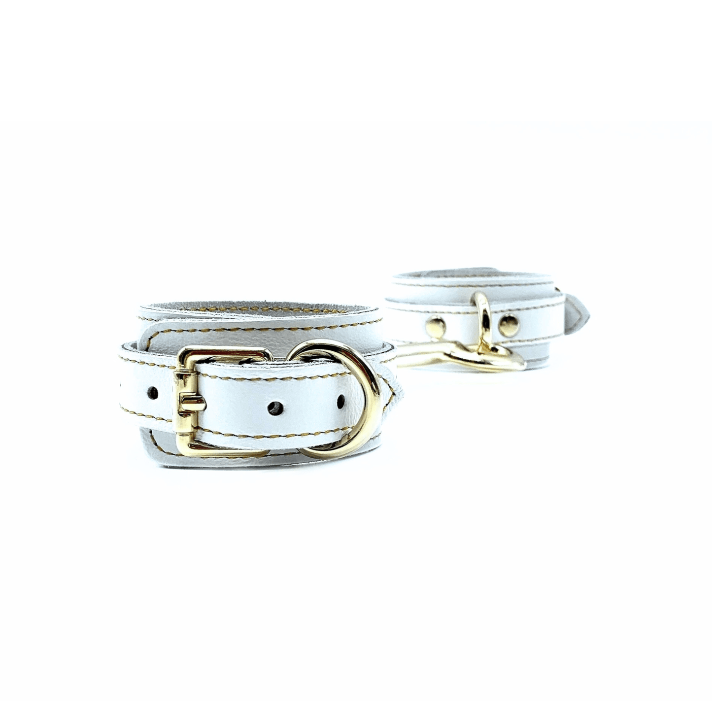 white leather ankle cuffs with gold buckle, and detailed gold stitching on white background.