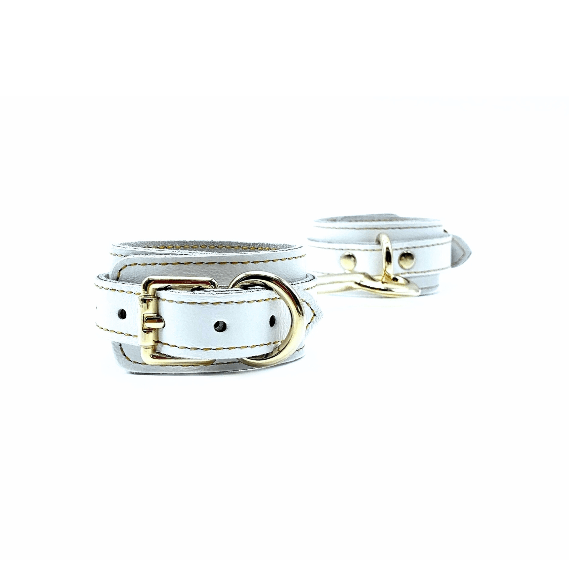 white leather ankle cuffs with gold buckle, and detailed gold stitching on white background.