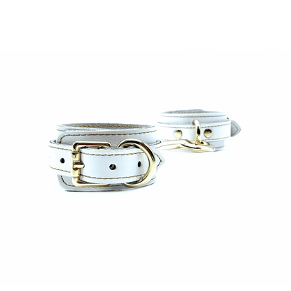 white leather ankle cuffs with gold buckle, and detailed gold stitching on white background.