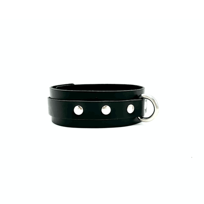 Side view of black leather collar focusing on silver D ring and 3 shiny rivets to the side of the ring. 