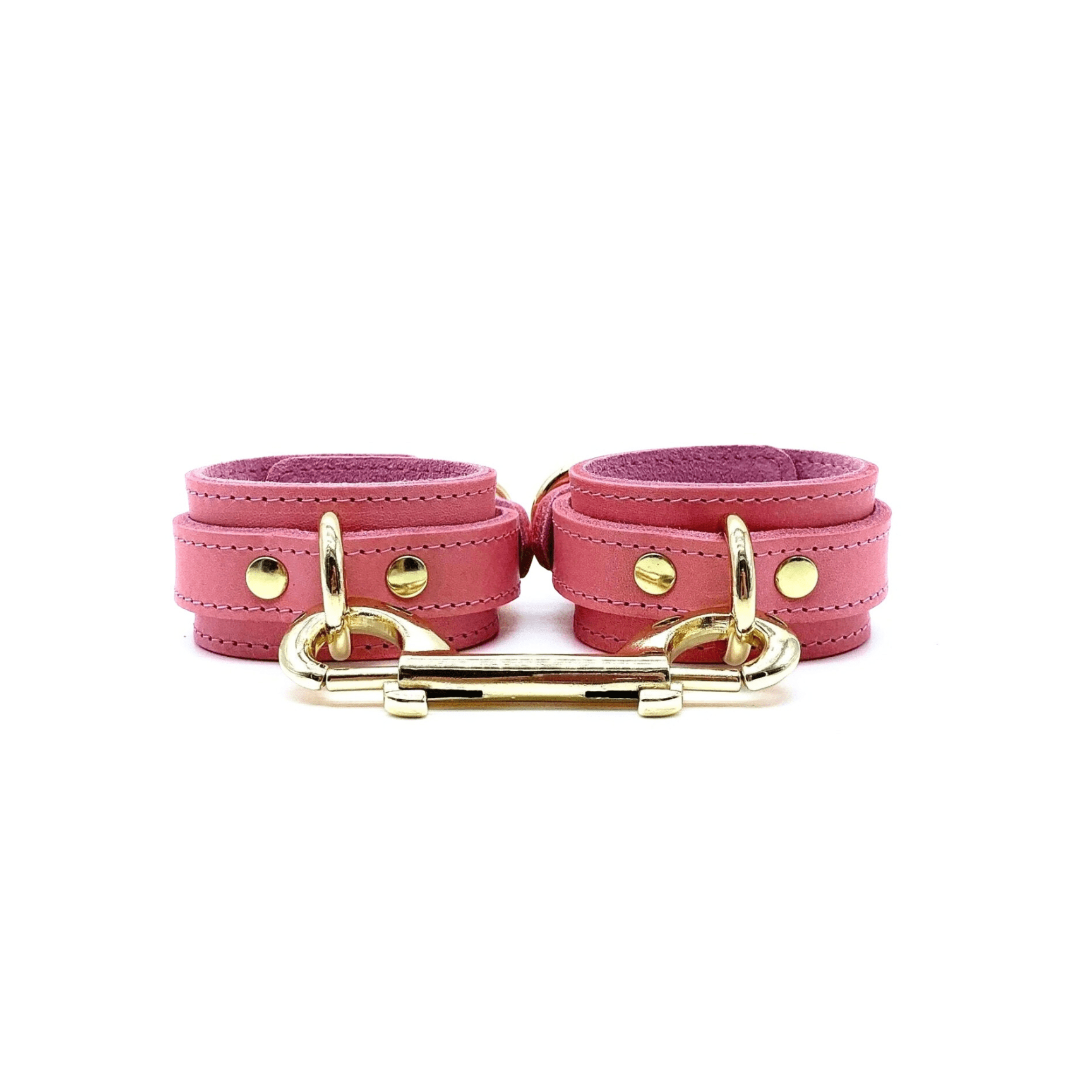 A pair of pink leather ankle cuffs with gold hardware, detailed stitching and double ended snap hook.