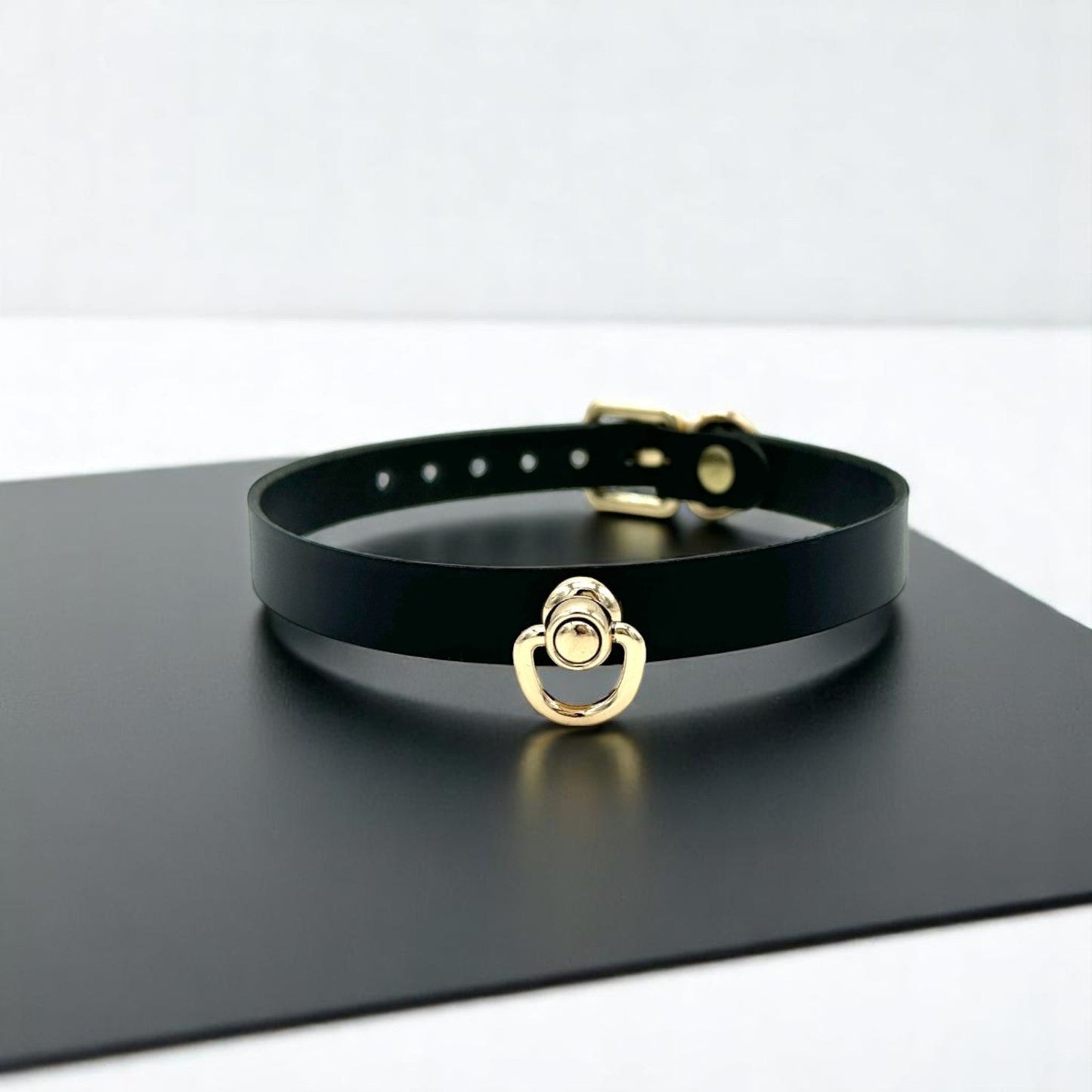Black Italian leather choker with gold hardware and center D-ring, minimalist collar design