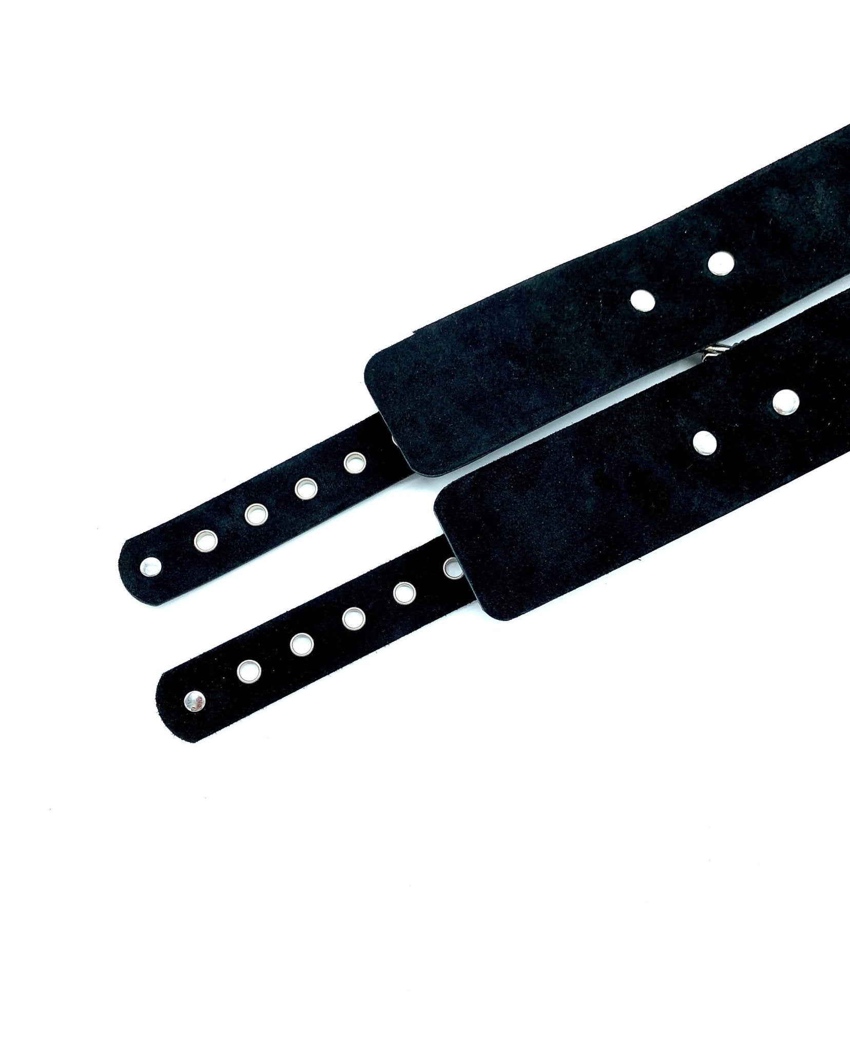 Italian 2" BDSM bondage cuffs made in the USA, positioned lying down to showcase the sumptuous black suede, providing a tactile and luxurious experience for those seeking refined restraint during intimate bondage encounters.