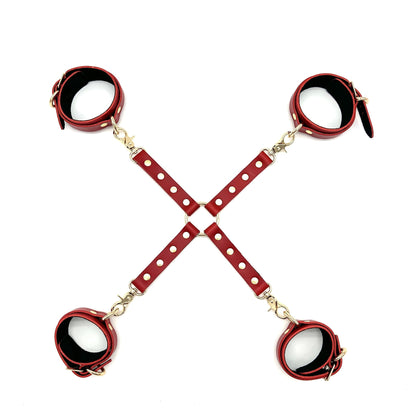 Red leather X or  hogtie connector with handcuffs and ankle cuffs, gold rivets, snap hooks and center O ring on background