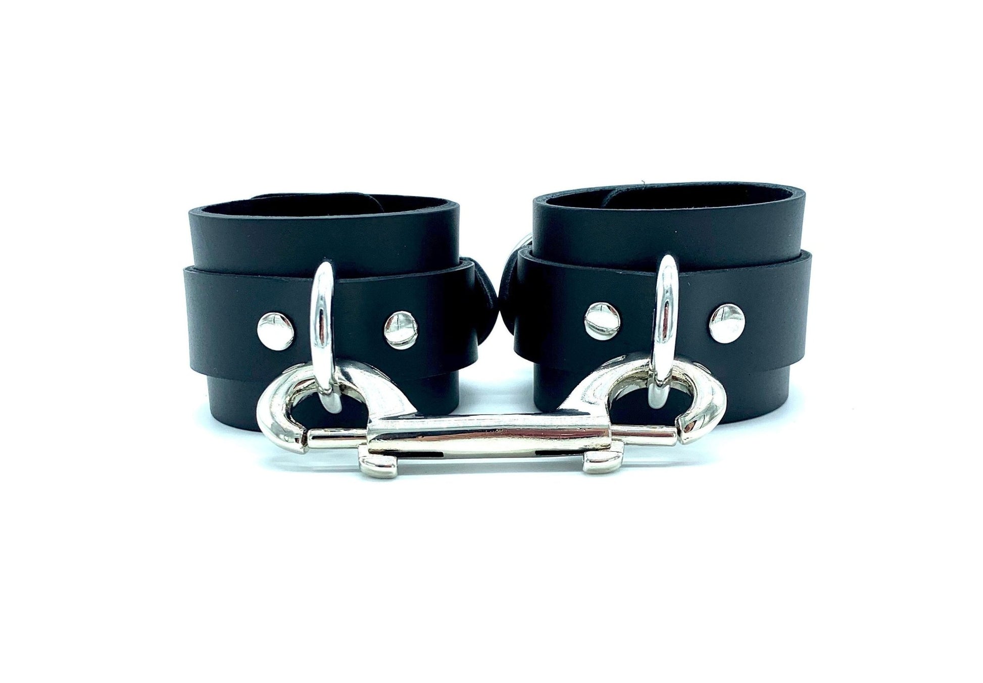 Black leather cuffs with matching black suede, connected by a silver connector featuring silver hardware, offering a sophisticated, monochrome look that combines modern style with traditional bondage functionality.