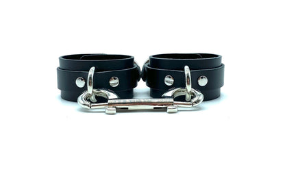 Black leather handcuffs with matching black suede, connected by a silver connector, combining a monochrome aesthetic with high-end functionality, ideal for those seeking discreet yet premium bondage accessories.