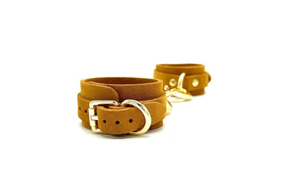 Italian suede BDSM bondage cuffs made in the USA, connected by a stylish connector that highlights the intricate gold buckle detail, accentuating the elegance and functionality of these high-quality cuffs designed for discerning bondage enthusiasts.
