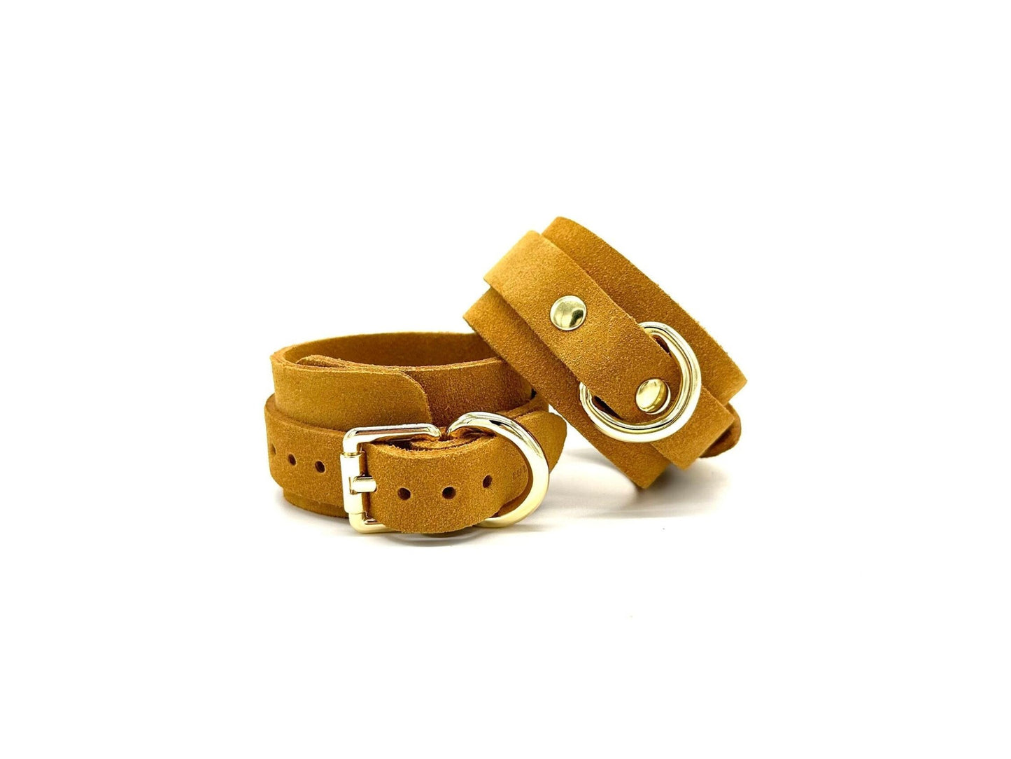 Pair of Italian suede BDSM bondage cuffs made in the USA, showcasing one cuff lying flat and the other placed on top, both embellished with gleaming gold hardware, offering a blend of sophistication and durability for captivating bondage experiences.