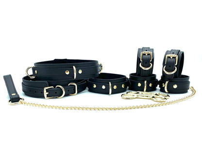 Complete set of seven Tango BDSM pieces including black leather cuffs with black suede and black stitching, all equipped with gold hardware, presenting a comprehensive and luxurious bondage kit for extensive play options.