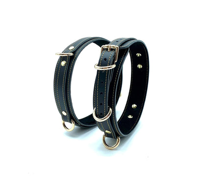 Standing Up: Tango Black Italian leather BDSM bondage thigh cuffs standing upright, displaying the structured design and consistent gold stitching on premium Italian leather.