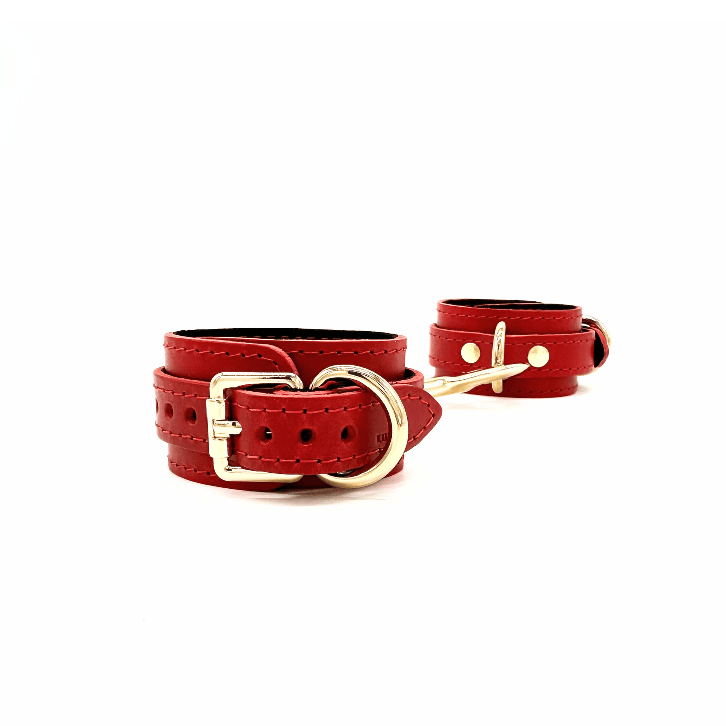 Red leather handcuffs with gold hardware, paired adjustable cuffs with smooth leather finish