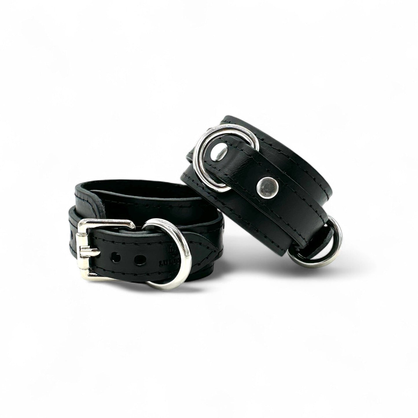 Black leather handcuffs close up with silver hardware, rivet detail and structured design