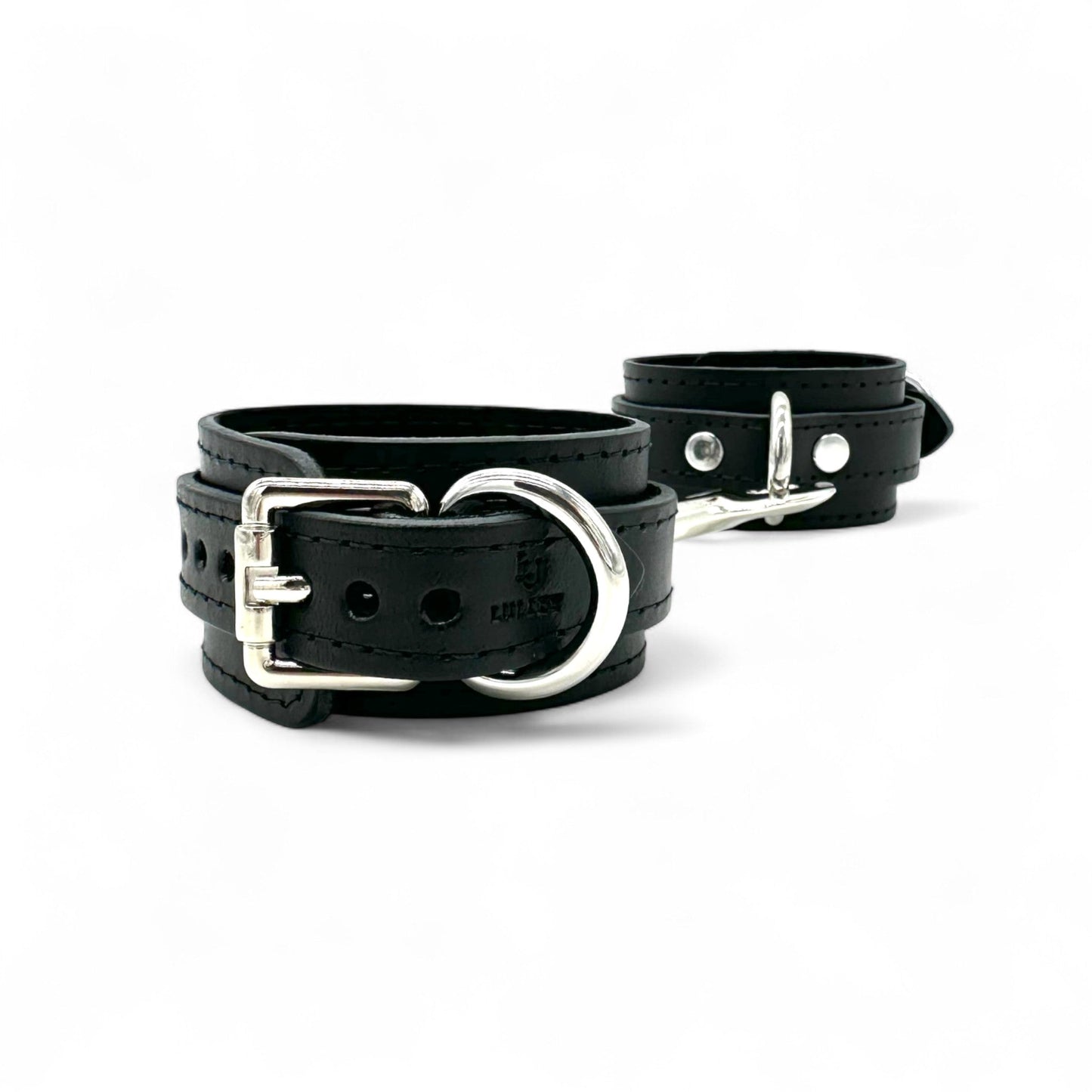 Black leather handcuffs with silver hardware and buckle closure, adjustable wrist restraint cuffs