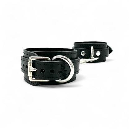 Black leather handcuffs with silver hardware and buckle closure, adjustable wrist restraint cuffs