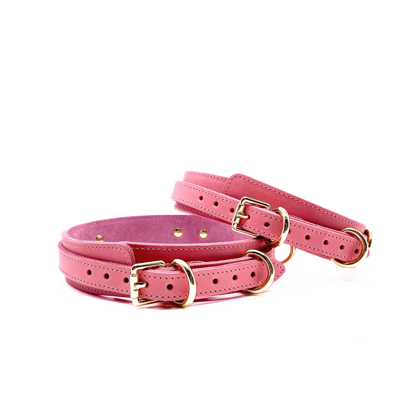 Pink leather thigh cuffs with shiny gold buckles, stitched outline and gold D-rings. 