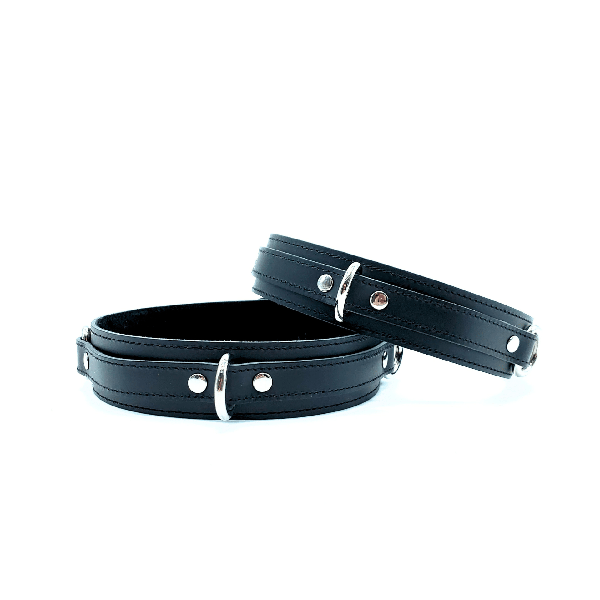 Black leather thigh cuffs with detailed black stitching and silver D rings for easy connection with other bondage restraints.