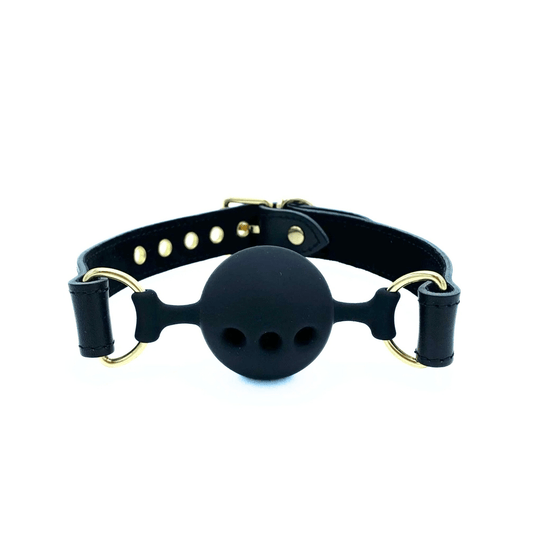 Black leather ball gag with adjustable strap, black silicone ball with breathing holes, and gold hardware on white background