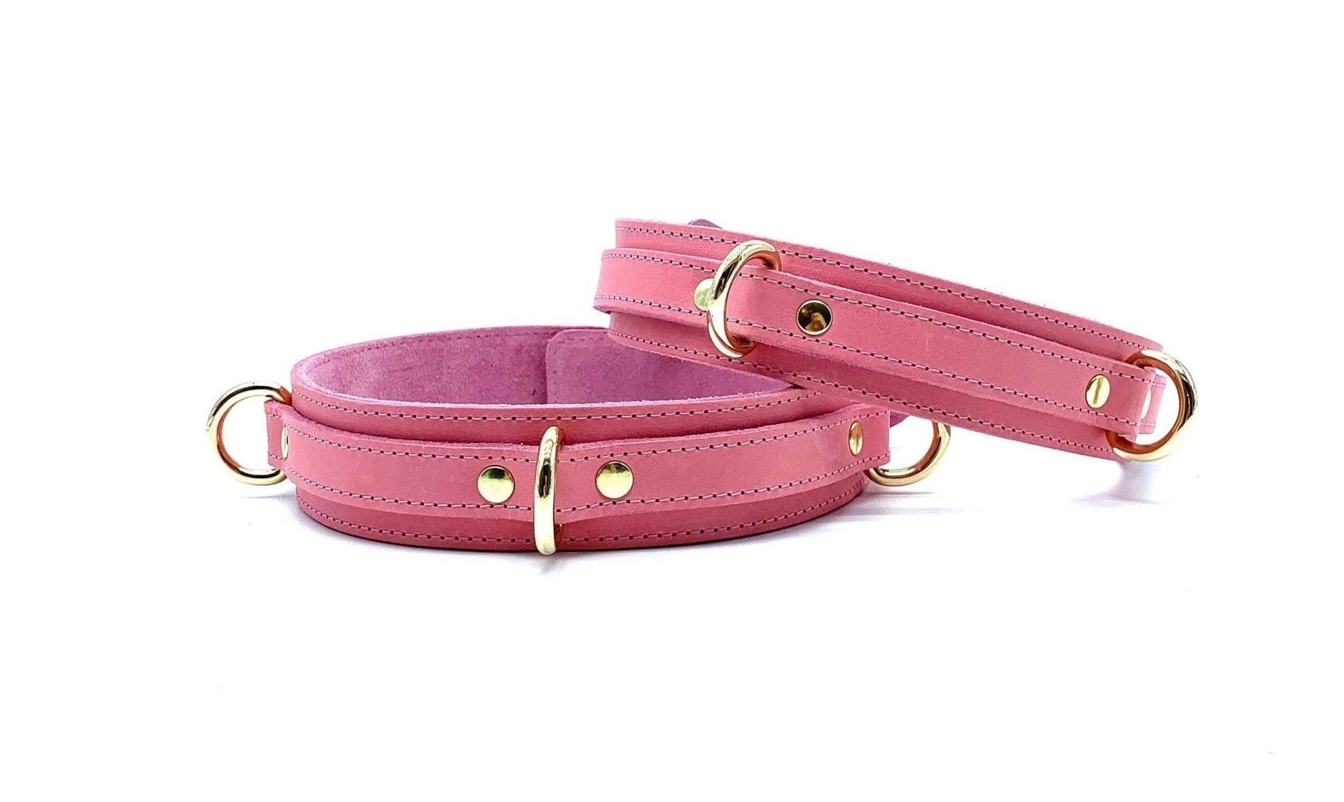 Front view of Tango Pink Italian leather BDSM bondage thigh cuffs, showcasing the vibrant pink leather with polished gold hardware, set against a clean, white background.